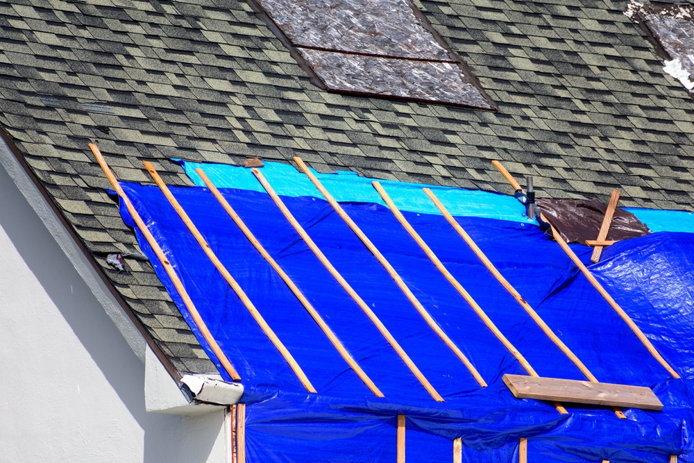 Residential roof covered with emergency tarp after storm damage